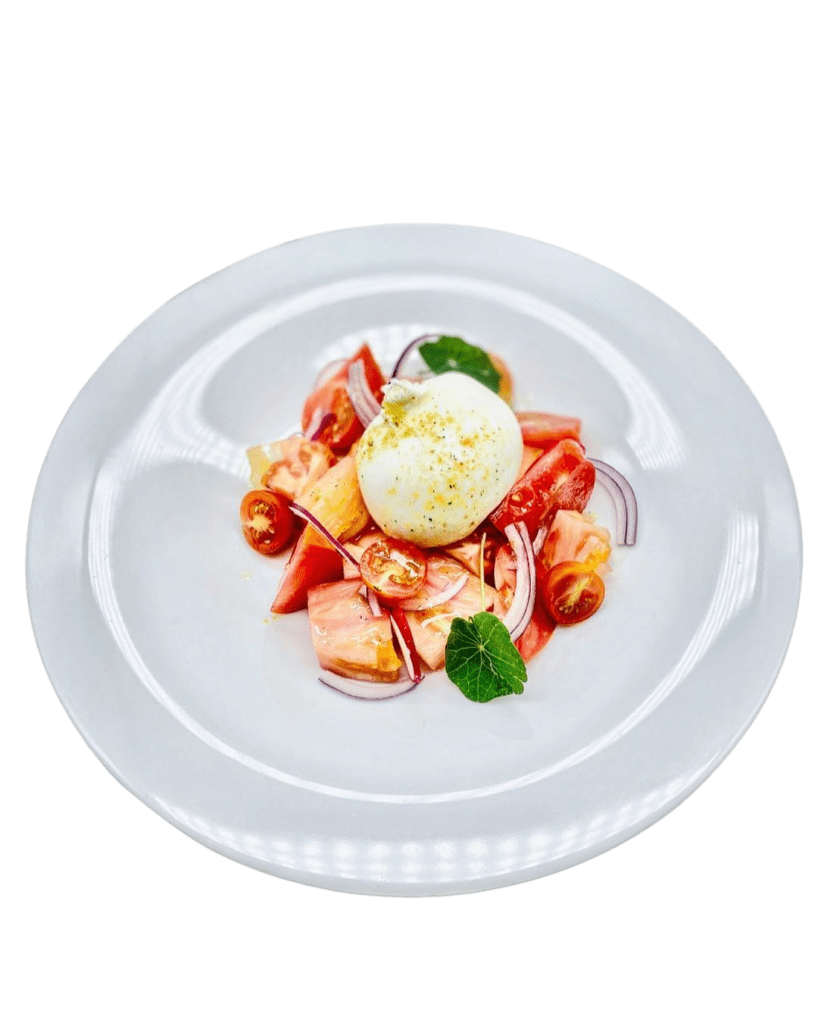 Plato de temporada, tomates raf y cherris con cebolla morada fresca y burrata, con toques de hoja de Capuchina y vinagreta de pistacho. Productos de temporada y proximidad al provenir del huerto orgánico del chef Jose Cuesta. Imagen con derechos de autor