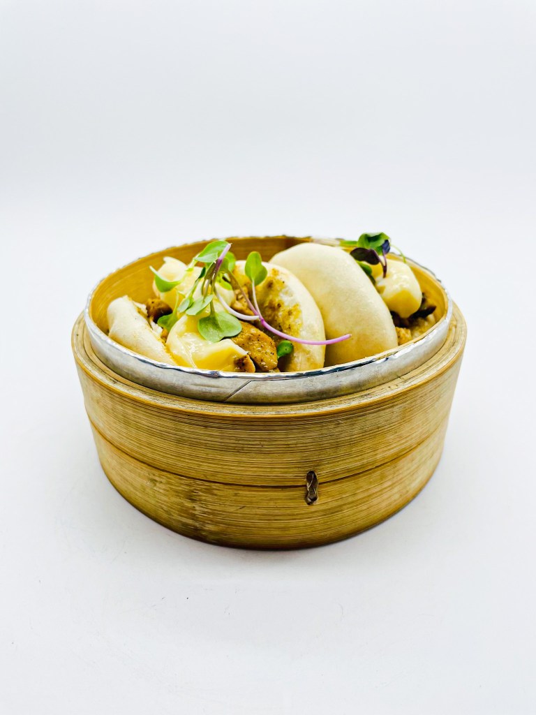 Cesta de Panes bao caseros, rellenos de pollo a baja temperatura con puntos de alioli emulsionado y brotes de rabanitos orgánicos. Imagen con derechos de autor