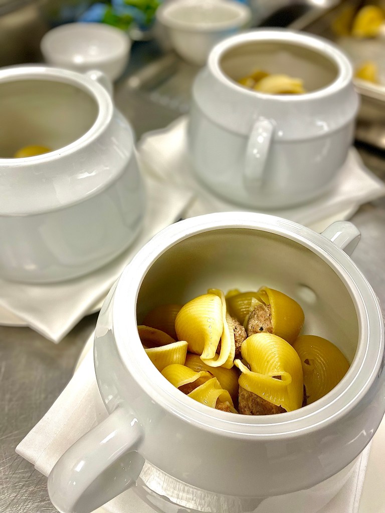 La imagen muestra una elegante presentación de galets rellenos en cazoleta individual, un plato típico de la gastronomía catalana ideal para la temporada de invierno. Perfecto para celebraciones navideñas o reuniones familiares, con un relleno de carne que aporta un sabor reconfortante y tradicional. Un clásico de la cocina mediterránea que destaca por su sencillez y sabor.